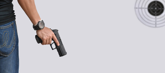 A gun shooter holds 9mm automatic pistol in right hand in front of the gun shooting range, concept for security, robbery, gangster and bodyguard training around the world. selective focus on pistol.