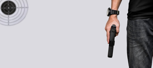 A gun shooter holds 9mm automatic pistol in right hand in front of the gun shooting range, concept...
