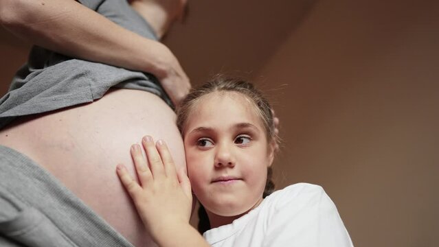 pregnant woman close-up belly. a little girl hugs her mother belly. happy family baby pregnancy newborn concept. baby listening to pregnant mother belly. happy family expecting daughter newborn