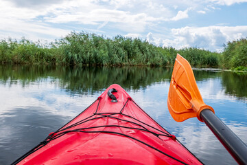 Kayaker point of view. Red kayak bow with a view on the river and rushes.   River kayaking concept....