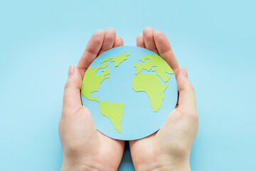 World environment day concept. Two human hands holding paper earth globe isolated over blue background