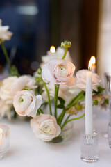 Banquet table decorated with plates, cutlery, candles, glasses and flower arrangements