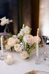Banquet table decorated with plates, cutlery, candles, glasses and flower arrangements