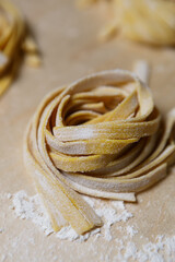 Raw tagliatelle pasta nest being on wooden table. Traditional Italian food cooking