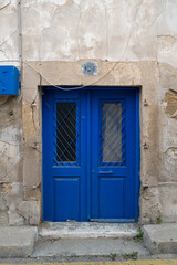 Entrance door of an old somewhat shabby house with two wings painted in a dark blue.