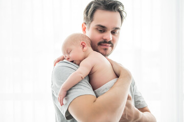 A Portrait of a father, with her nursing baby on bedroom close to a window