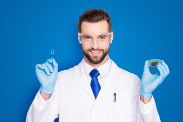 Portrait of attractive biologist in white outfit with tie, showing having forceps and vial with...
