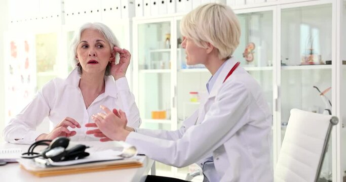 Doctor talking to elderly patient woman with poor hearing in clinic 4k movie slow motion 
