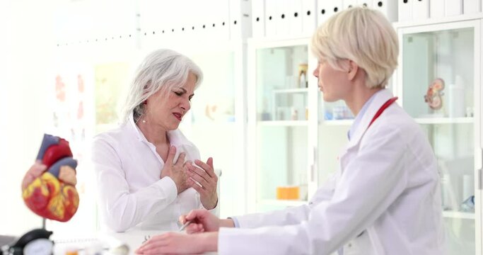 Elderly female patient complaining of pain in heart to doctor in clinic 4k movie slow motion 