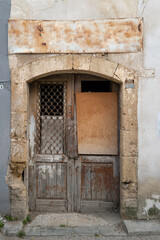Fototapeta na wymiar Very old and shabby entrance door made of two wings of a small workshop. 