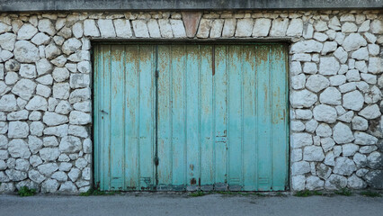 street view of rusty blue garage door against stone wall