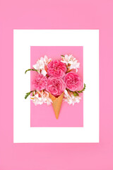 Surreal rose and freesia flower ice cream cone Composition. Creative nature food gift concept for Valentines birthday anniversary or Mothers Day. White frame on pink background. 