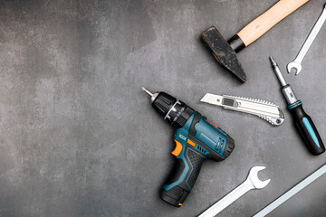 Hand tool set on dark board. Cordless drill, screwdriver, hammer, wrench, cutter. Flat lay, top view