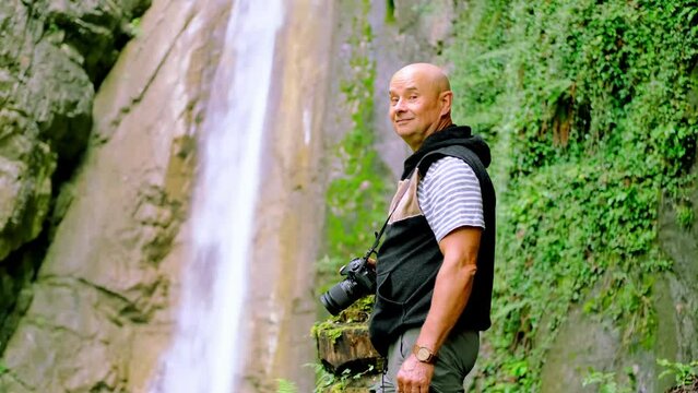 photographer, man admires landscape, waterfall giessbach in alpine mountains, fast flowing powerful stream of clear water, splashes scatter, concept of wild nature, natural resources, active tourism