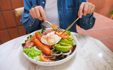 Closeup image of a woman eating salad and drinking coffee in cafe