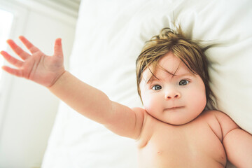 Fototapeta na wymiar Portrait of cute adorable white Caucasian baby girl lay on a white bed