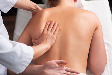 masseur massaging back and shoulder blades of young woman on massage table. Concept of massage spa treatments. Close-up
