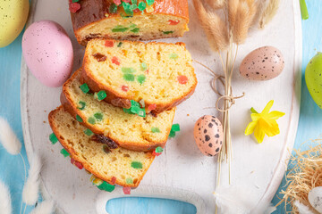 Sweet Fruitcake for Easter surrounded by eggs and spring flowers.