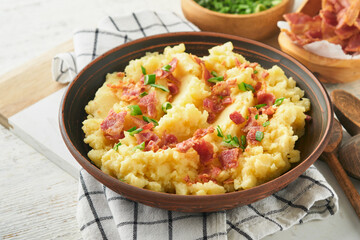 Mashed boiled potatoes. Bacon mashed potatoes with green onion, pepper and cheddar cheese in bowl on light old wooden backgrounds. Delicious creamy mashed potatoes. Top view.