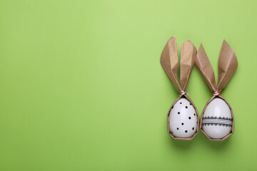 Easter bunnies made of craft paper and eggs on light green background, flat lay. Space for text