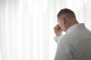 Fototapeta premium A modern man mourns while standing at the window