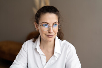 A businesslike woman with glasses in the office, a manager in a white shirt coworking space.