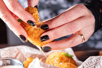 Woman's hand holding fried mozzarella cheese ball