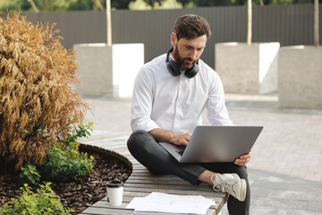 Businessman sitting in urban area and working on laptop