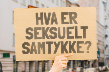 The question " What is sexual consent? " on a banner in men's hands with blurred background. Intimacy. Intimate. Sex. Adult. Law. Relationship. Love. Legality