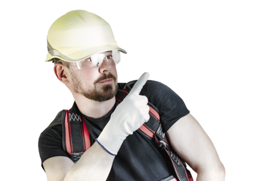 Positive friendly bearded male builder in overalls, hardhat and goggles pointing with his finger. Isolated background.