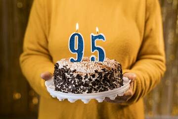 Happy birthday. Woman holding fresh delicious birthday cake with burning candle number 95, close...