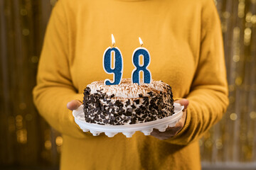 Happy birthday. Woman holding fresh delicious birthday cake with burning candle number 98, close...