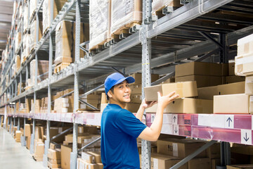 Naklejka na ściany i meble Asian man holding bundles of paper from stock on shelves in warehouse