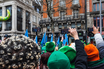 Hands with phones, people taking pictures green costumes and green hats, people, Saint Patrick parade Dublin centre, Ireland