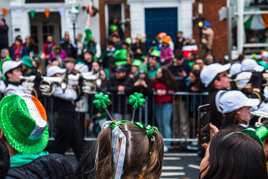 Girl with green clover headband, green outfit, crowd in green hats in background, watching the parade march in Dublin city center, Saint Patricks day, Ireland