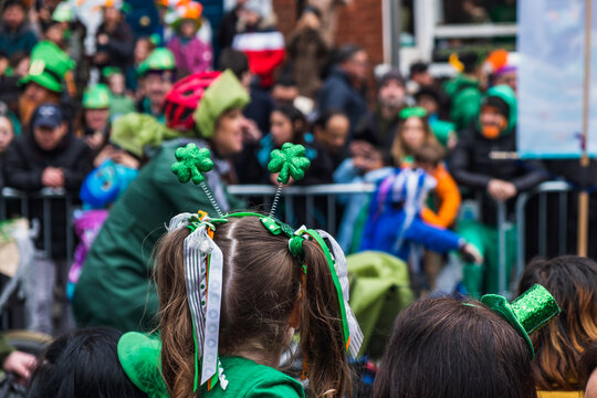 Girl with green clover headband, crowd and green hats in background, watching the parade march in Dublin city center, Saint Patricks day, Ireland