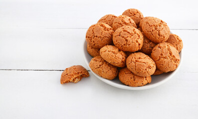 Traditional Italian almond cookies amaretti  in a plate on a white wooden background.Famous amarettini cookie biscuits.Delicious pastry popular in Italy.Selective focus.