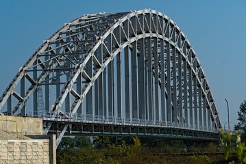 Naklejka premium arch shaped road bridge over the river canal