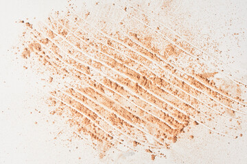 A neutral-colored face powder applied to a surface on a light background. Top view, flat position. With space to copy. Powder texture. High quality photo