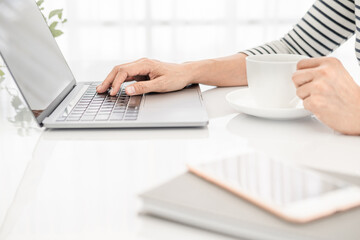 Asian business woman in casual clothes, Hand typing text on laptop in a bright modern office with copy space.