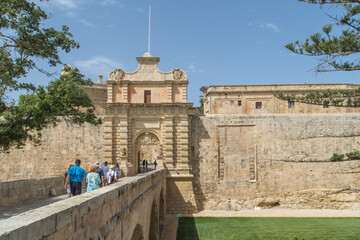 Mdina, Malta - June: Tourists on the bridge over the ditch leading to the Mdina City Gate.