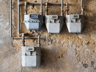 Old methane or propane gas meter placed on a damaged plaster wall