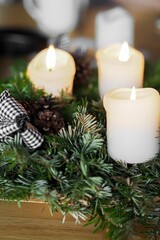 Vertical shot of the Christmas decoration with white candles and spruce branches