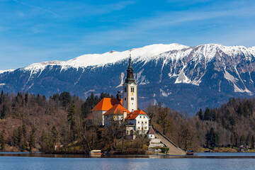 Snow capped mountain background of Lake Bled Church of the Assumption of Maria in Slovenia