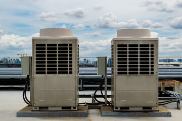 Air conditioner units (HVAC) on a roof of industrial building with blue sky.