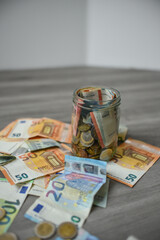 Money jar filled with Euro banknotes and coins