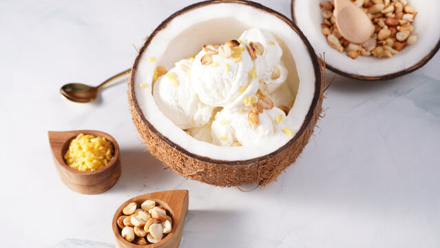 Coconut ice cream topped with roasted peanuts in a coconut shell macro shot. (spot focus)
