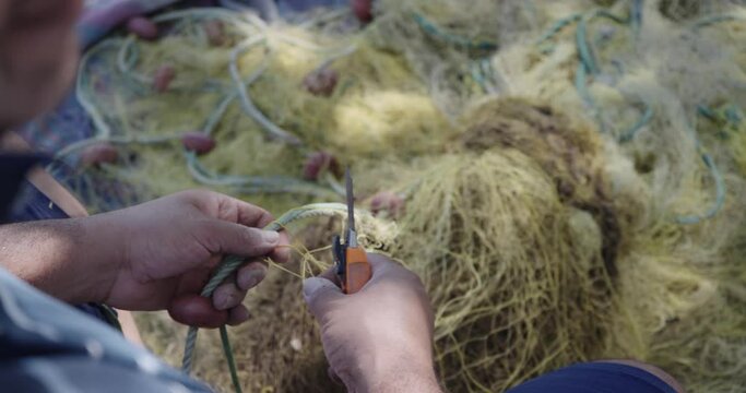 Fisherman repair a fisherman net with floating balls on pier in Corfu island, Greece, slow motion