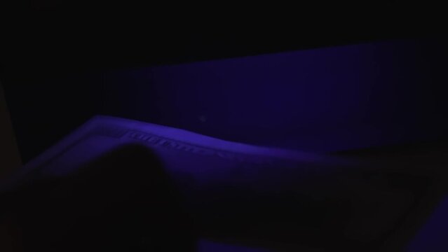 verification of counterfeit money in ultraviolet. UV check of USD banknotes. Money falsification concept background. In-depth inspection equipment. Equipment for in-depth inspection of money
