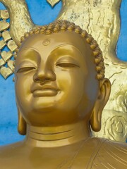 Golden Buddha statue with blue and yellow decorative ornaments in the background